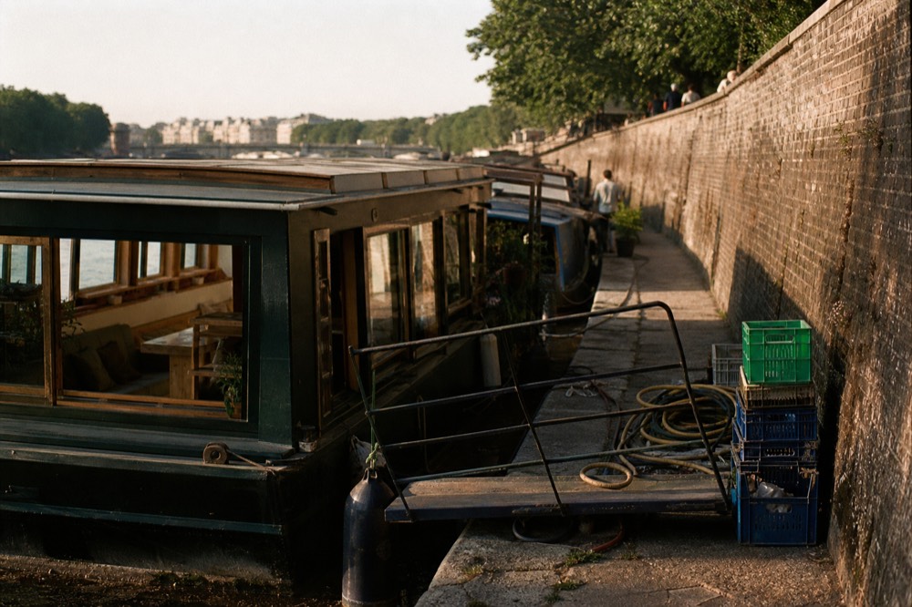 A modern flat-roofed ark houseboat moored beside a brick quay wall in Amsterdam, no text, no logos, no people
