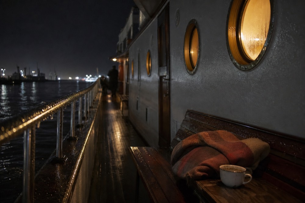 A vintage saloon boat with warm interior lights moored on an Amsterdam canal at night, no text, no logos, no people