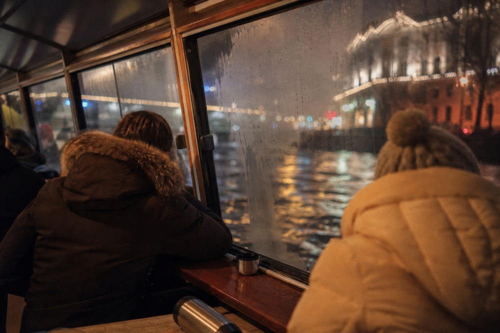 Passengers wrapped in winter coats on a covered canal boat at night in Amsterdam, no text, no logos, no people
