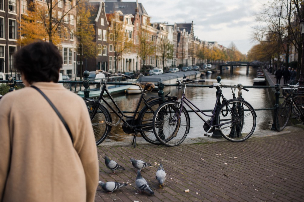 Classic Amsterdam canal scene with narrow gabled houses and bicycles on a bridge, no text, no logos, no people