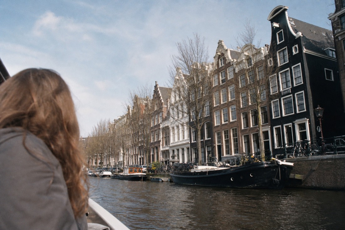 Daytime view along the Herengracht showing canal house facades and gables from the water, no text, no logos, no people.