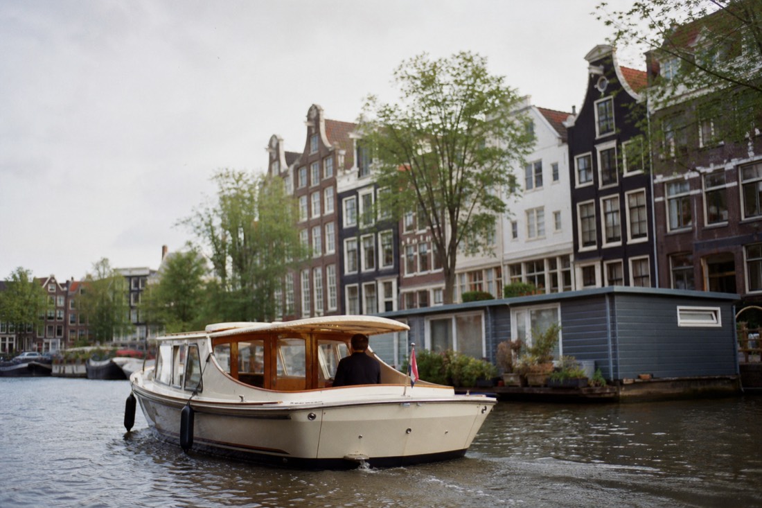 A classic saloon boat gliding along the Prinsengracht past narrow gabled houses, no text, no logos, no people.