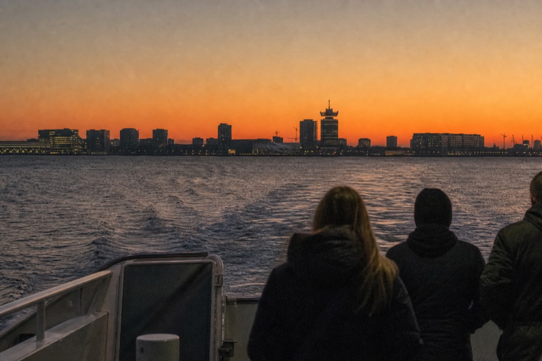 A free ferry crossing open water toward Amsterdam Noord at dusk, no text, no logos, no people.
