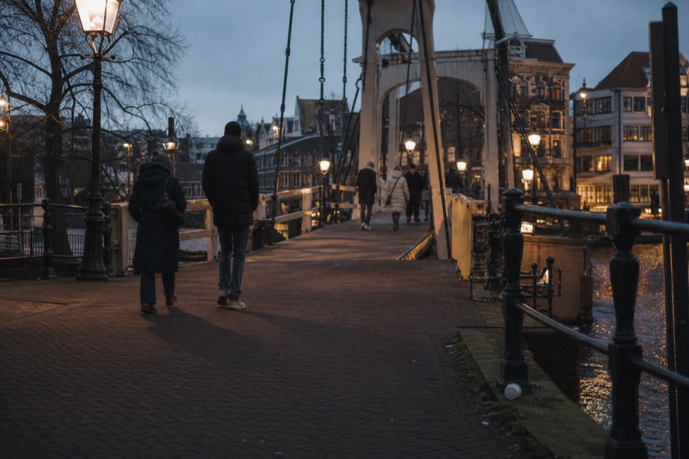 Pedestrians crossing a classic Amsterdam drawbridge at dusk, no text, no logos, no people