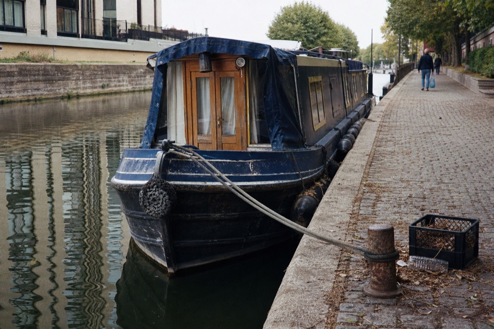 A canal boat moored at a boarding point along a narrow Amsterdam gracht, no text, no logos, no people