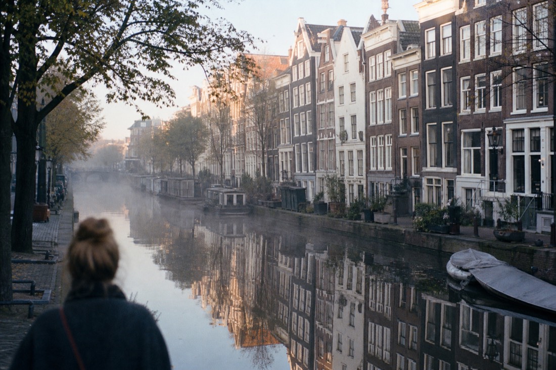 Amsterdam canal houses reflecting in still morning water, no text, no logos, no people