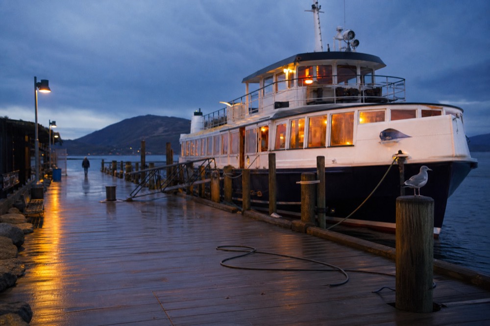 A queue-free canal cruise pier in Amsterdam with a boat waiting at dusk, no text, no logos, no people