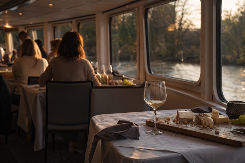 A canal cruise boat interior with set tables of wine glasses and Dutch cheese boards, no text, no logos, no people