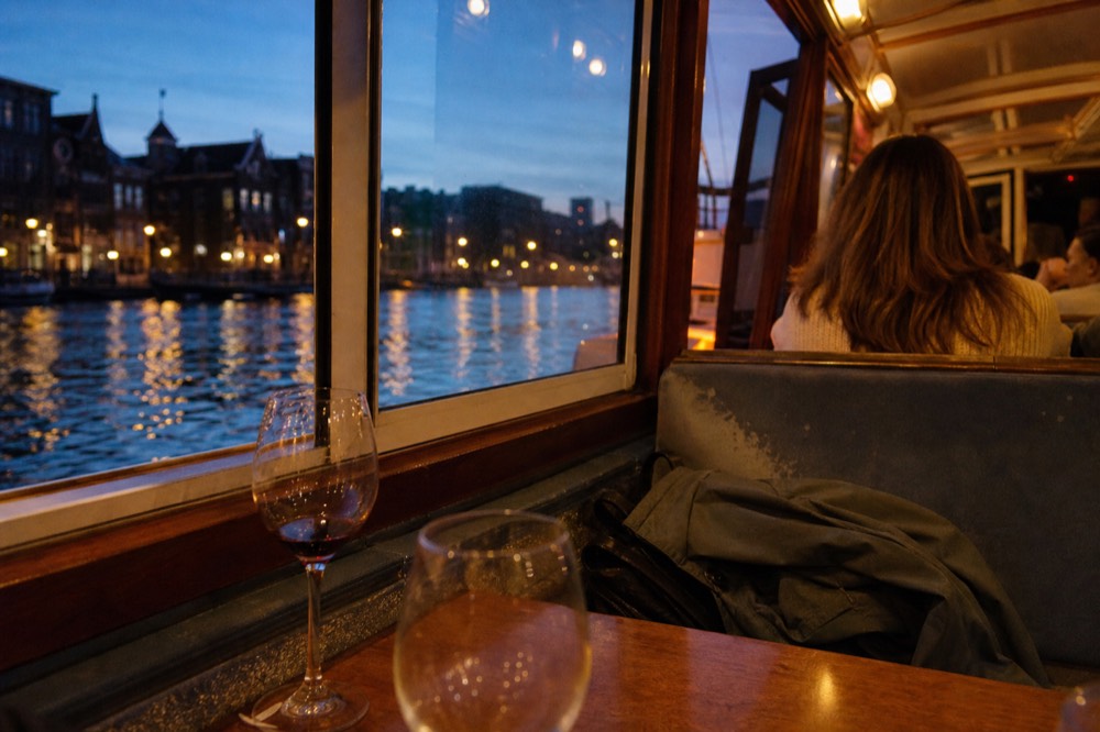 Canal cruise boat interior with wine glasses on a table at dusk, no text, no logos, no people