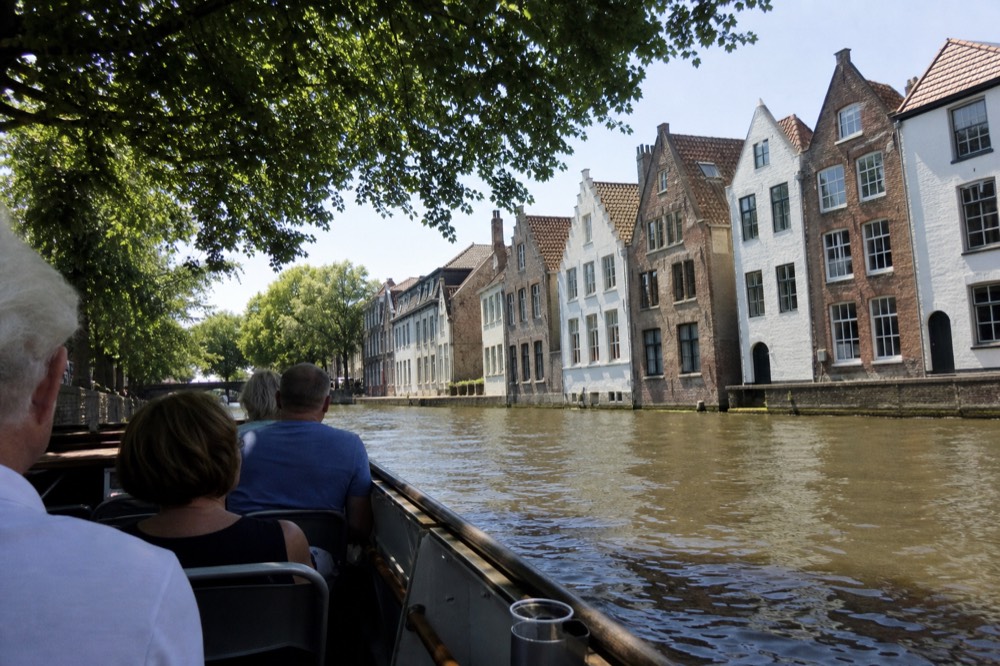 Open canal cruise boat passing a row of Amsterdam gabled houses in daylight, no text, no logos, no people