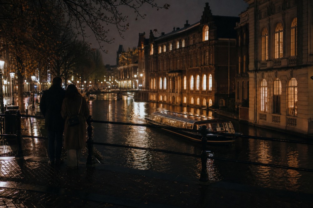 Evening canal cruise boat gliding past illuminated Amsterdam facades, no text, no logos, no people
