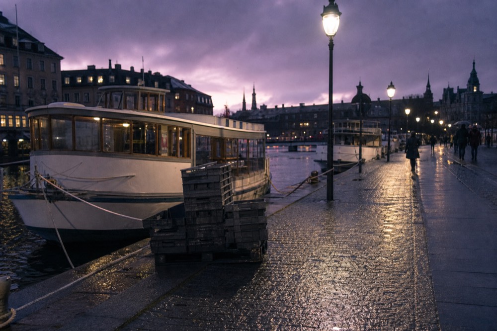 Canal cruise boarding point on the Amstel near Central Station at twilight, no text, no logos, no people