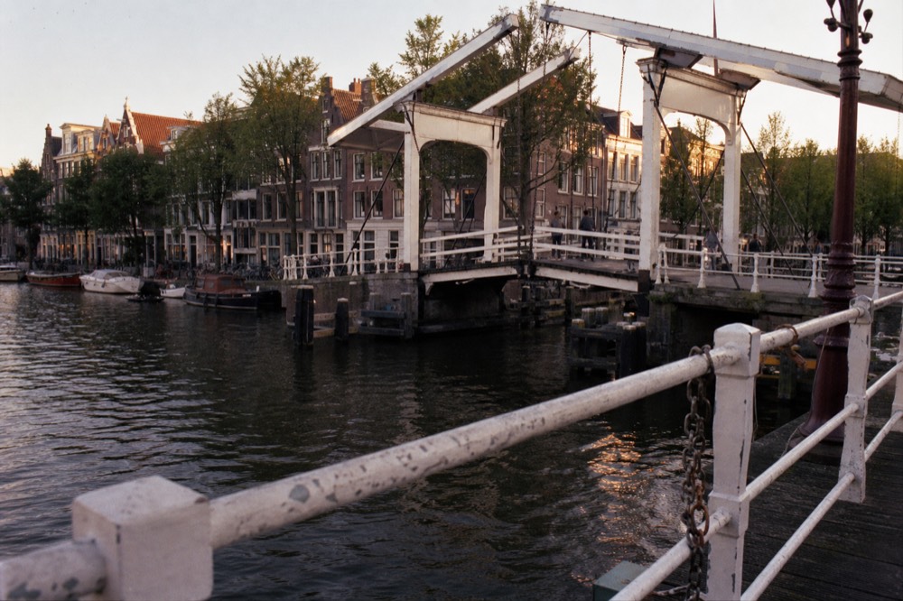 A classic Amsterdam drawbridge over a canal with gabled houses behind, no text, no logos, no people.