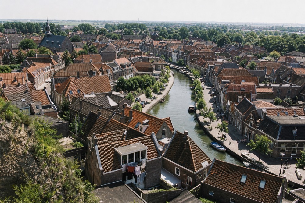 Concentric Amsterdam canals lined with narrow gabled houses seen from above, no text, no logos, no people