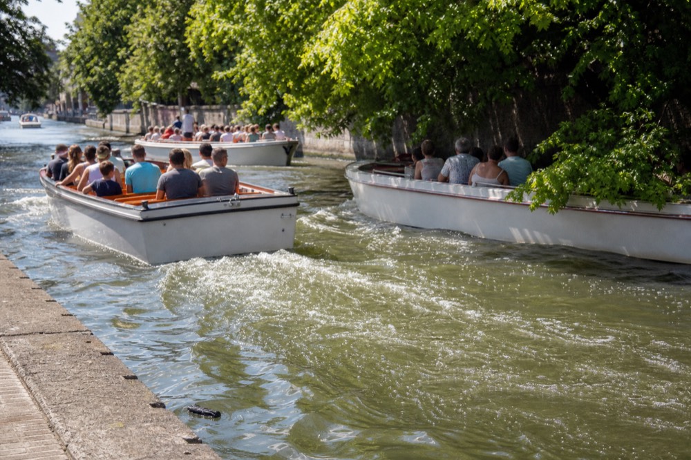 Several canal cruise boats passing each other on a narrow Amsterdam canal, no text, no logos, no people
