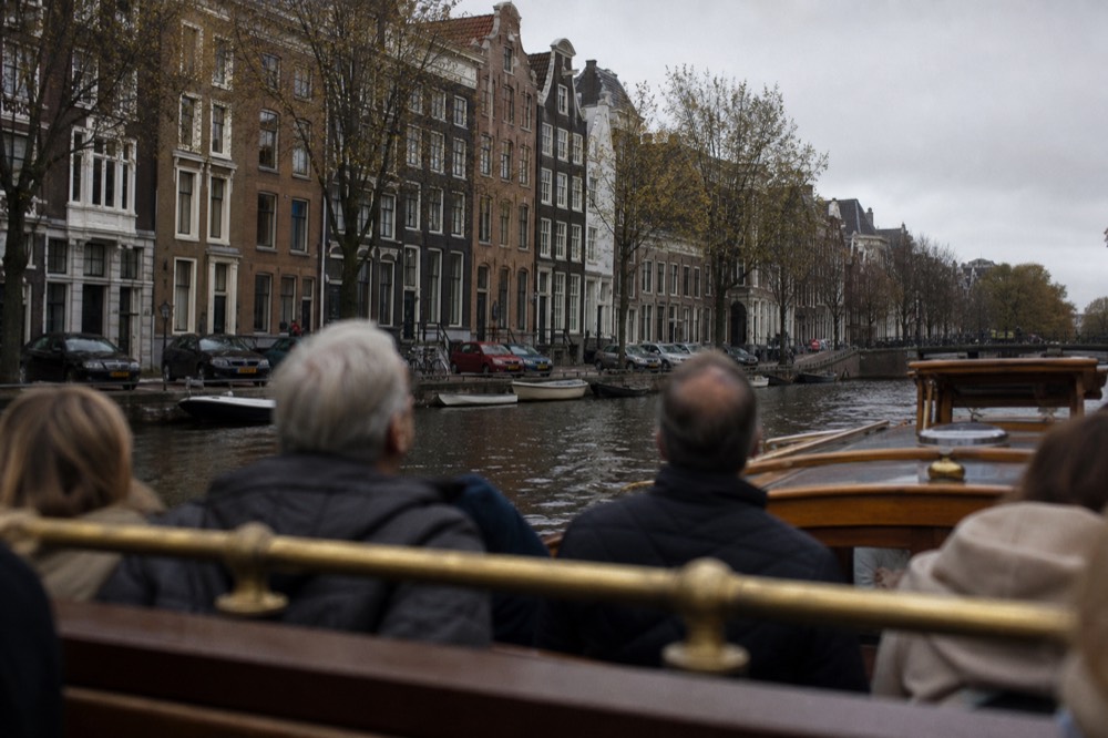 Passengers on a small canal cruise boat looking up at canal-side houses, no text, no logos, no people