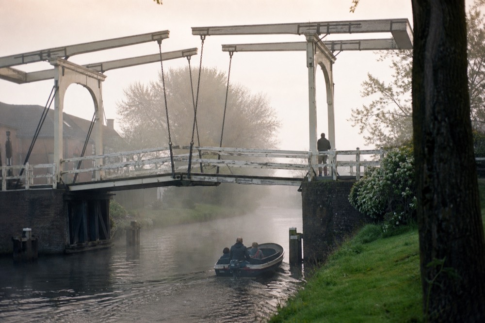 Classic Amsterdam drawbridge over a canal with a small boat passing underneath, no text, no logos, no people