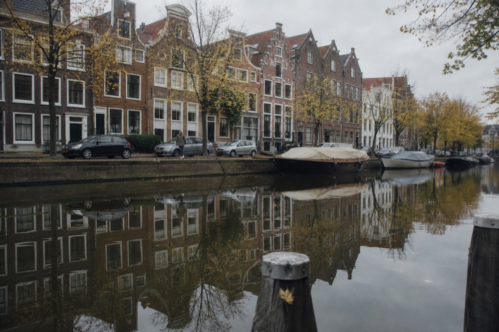Row of Golden Age gabled facades reflected in a calm Amsterdam canal, no text, no logos, no people