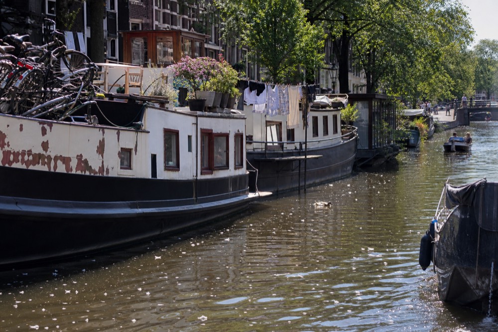 Houseboats moored along an Amsterdam canal with bicycles on deck, no text, no logos, no people