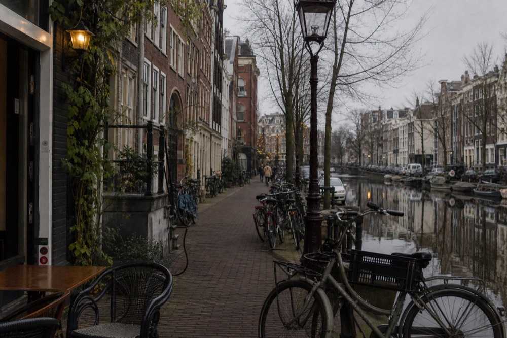 Narrow Jordaan street with bicycles and a small café terrace, no text, no logos, no people
