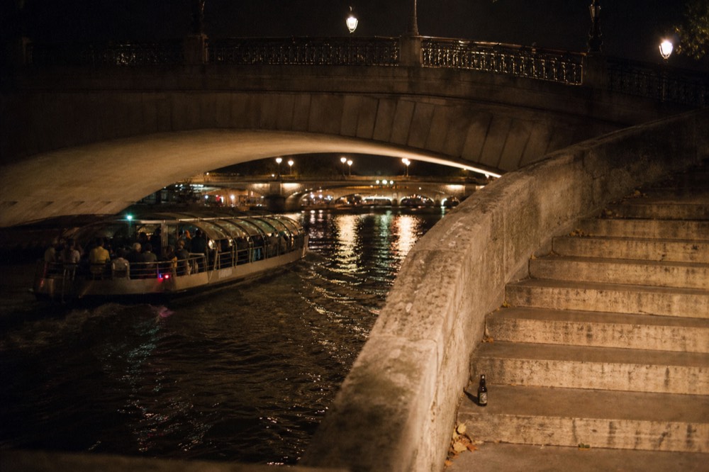 An evening canal cruise passing lit bridges in Amsterdam after dark, no text, no logos, no people